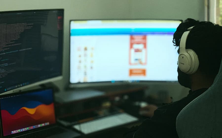 A web designer working across a modern multi-screen workspace